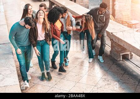 Gruppo misto di giovani che sorride e hanno camminato insieme e chiacchierato all'aperto per strada. Concetto di stile di vita per ragazzi e ragazze. Teal e o Foto Stock