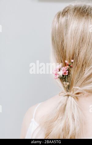 Concetto femminile, delicato, bellezza, bello, fiori selvatici, fiori nei capelli delle donne, ragazza, coda lunga di pony dei capelli, concetto femminile, natura, naturale, marrone Foto Stock