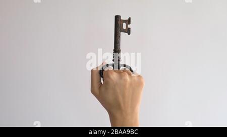 Cavatappi per aprire bottiglie sotto forma di chiave nel pugno di una donna. Foto Stock