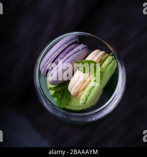 Macaron o macaron alla menta e lavanda viola fatti in casa su sfondo scuro Foto Stock