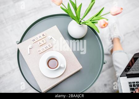 Fiori, libri e una tazza di caffè su un tavolo rotondo all'interno, vista dall'alto. Lavoro a casa e atmosfera accogliente casa concetto Foto Stock