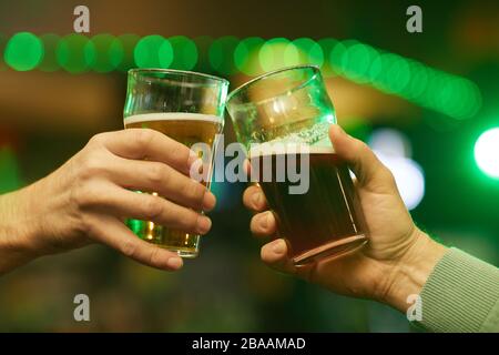 Primo piano di due mani maschili con bicchieri di birra e tostatura Foto Stock
