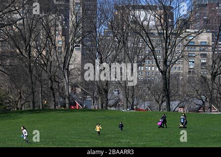 New York, Stati Uniti. 26 marzo 2020. Praticare il divaricamento sociale, due donne e portare i bambini a giocare in Sheep's Meadow all'estremità sud di Central Park, a New York, NY, 26 marzo 2020. Lo Stato di New York sta vedendo il più alto numero di casi negli Stati Uniti, con (a partire da questo scritto) più di 37,000 casi positivi testati di COVID-19 e più di 21,000 a New York City. (Anthony Behar/Sipa USA) Credit: Sipa USA/Alamy Live News Foto Stock