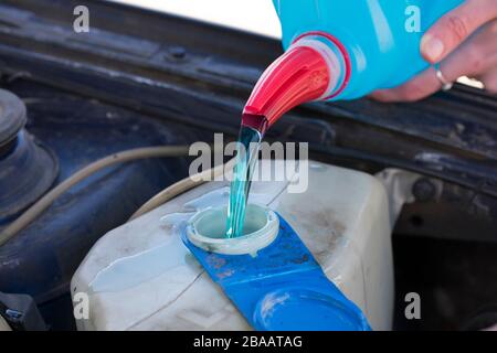 Versare il liquido di lavaggio con schermo blu in auto. Mani femminili Foto Stock