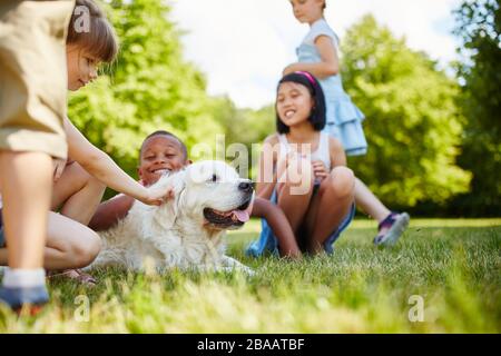 I bambini che accarezzano il cane del ritrovo d'oro in giardino d'estate Foto Stock