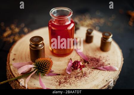 Olio di erbe su piastra di legno con fiori Foto Stock