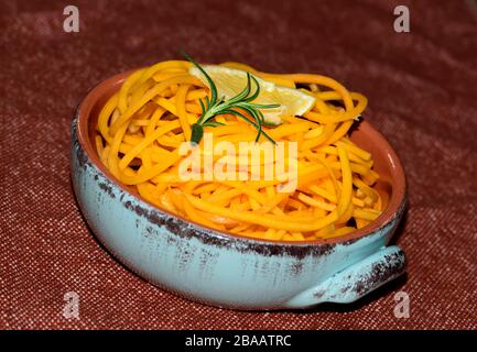 Noodles di zucca di Butternut organici in una ciotola con una fetta di limone e rametto di erbe di Rosemary Foto Stock