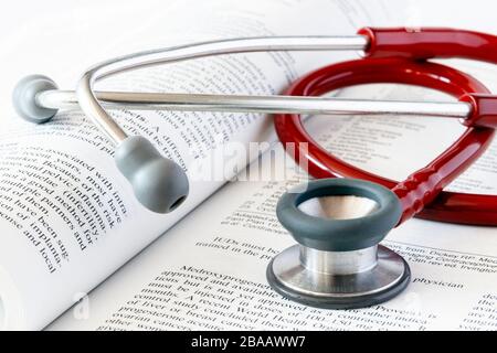 Uno stetoscopio rosso su un manuale medico aperto Foto Stock