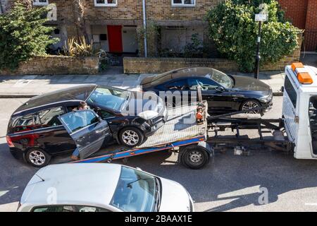 Un'auto è stata incavata sul retro di un camion di recupero in una strada residenziale nel nord di Londra, Regno Unito Foto Stock