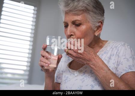 Donna caucasica senior che prende il suo farmaco a casa Foto Stock