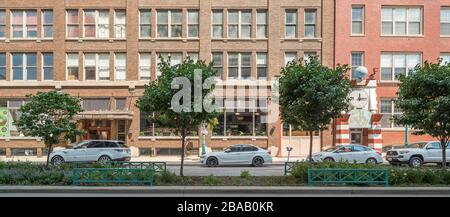 Automobili e alberi di fronte a negozi e loft in ristrutturato terzo Ward magazzino, Milwaukee, Wisconsin, Stati Uniti Foto Stock
