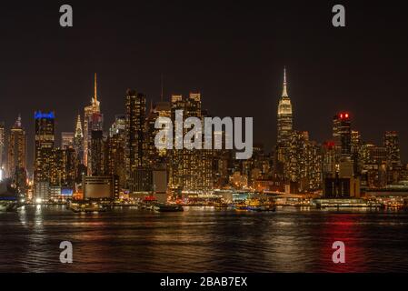 New York City Skyline Midtown con Empire state Building di notte con riflessi colorati sul fiume Hudson. Foto Stock