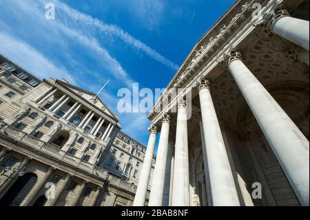 Vista soleggiata della facciata dell'edificio della Bank of England e dello storico Royal Exchange sotto il cielo blu luminoso nel centro finanziario della City di Londra, Regno Unito Foto Stock