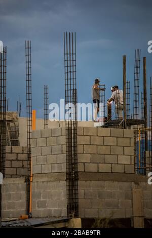 Due operai di costruzione lavorano o sul tetto, saldando la ringhiera metallica. Foto Stock