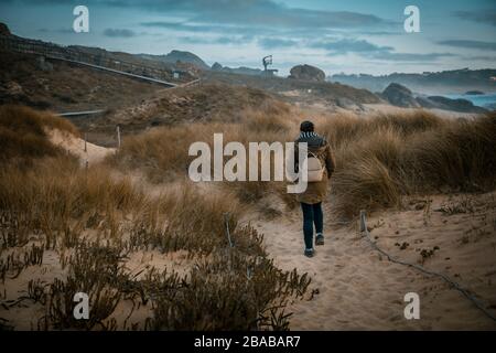 Donna che cammina attraverso una bella zona di dune sulla costa Foto Stock