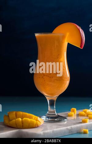 Frullato di mango fresco su sfondo blu. Bevanda fresca estiva. Frullato di frutta tropicale. Mango e zenzero sano frullato. Foto Stock