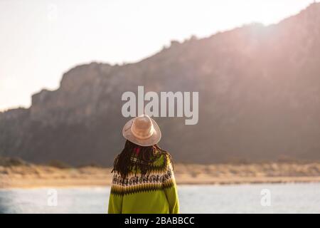 Giovane donna in un cappello sulla spiaggia al tramonto Foto Stock
