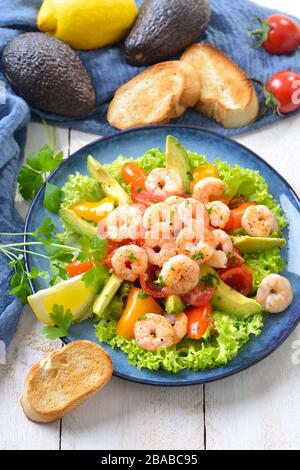 Deliziosa insalata di pomodori avocado con gamberi fritti e baguette tostate Foto Stock