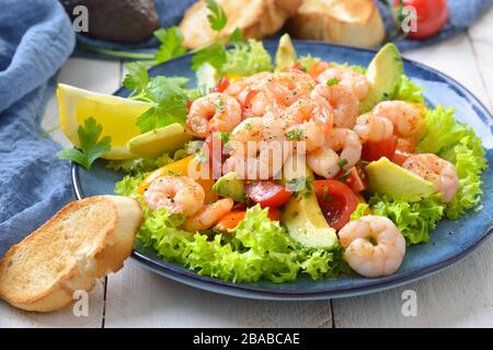 Deliziosa insalata di pomodori avocado con gamberi fritti e baguette tostate Foto Stock