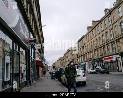 Persona che cammina a Glasgow indossando una maschera chirurgica per proteggere da infezioni durante il Pandemic britannico di Coronavirus e blocco. Foto Stock