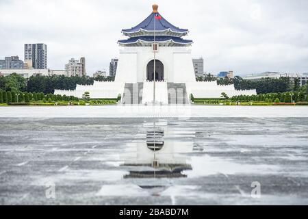 Vista mozzafiato della National Chiang Kai-Shek Memorial Hall in lontananza con la sua riflessione in un pouddle in primo piano. Foto Stock