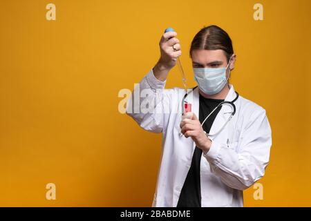 Medico giovane che misura la tensione usando un dispositivo di misurazione mentre indossa una maschera protettiva contro il virus sars-cov-2. Scatto in modalità orizzontale contro o Foto Stock