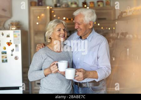 Felice coppia senior abbracciando nella loro casa Foto Stock