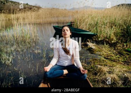 Donna meditando in natura.fuga da stressante reality.memore donna praticante meditation.Breathing technique.Mental state issues menagement. Foto Stock