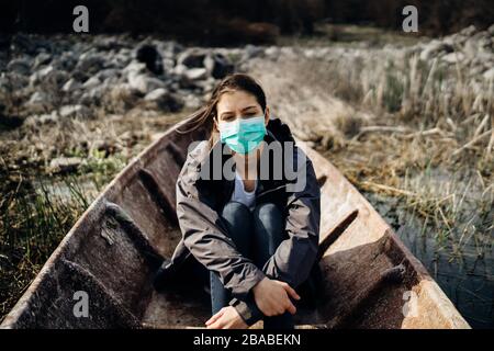 Donna con maschera in disperazione e paura di coronavirus.Mental Escape.Emotional preoccupato persona in boat.Imigrant.Apotalipse Salvation.Pandemic depressione Foto Stock