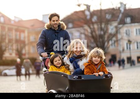 Giovane famiglia a cavallo in bicicletta da carico insieme Foto Stock