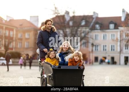 Giovane famiglia a cavallo in bicicletta da carico insieme Foto Stock