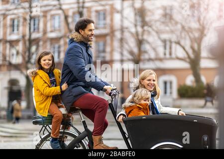 Giovane famiglia a cavallo in bicicletta da carico insieme Foto Stock