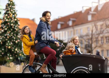 Giovane famiglia a cavallo in bicicletta da carico insieme Foto Stock