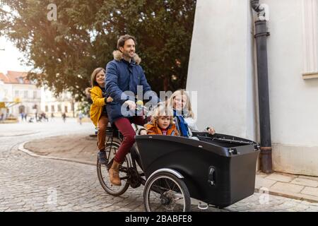 Giovane famiglia a cavallo in bicicletta da carico insieme Foto Stock
