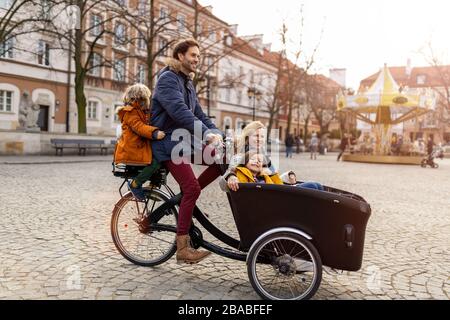 Giovane famiglia a cavallo in bicicletta da carico insieme Foto Stock