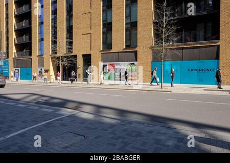 Londra UK, Royal Wharf Shopper accodarsi per i generi alimentari durante l'epidemia di Covid-19 Foto Stock