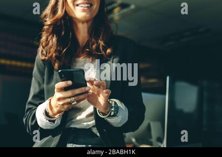 Colpo ritagliato di una donna d'affari con un sul cellulare in ufficio. dirigente d'azienda che utilizza un telefono in ufficio. Foto Stock