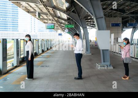 Tre persone asiatiche che indossano la maschera in piedi distanza di 1 metro da altre persone mantenere la distanza proteggere da virus COVID-19 e persone sociale distancina Foto Stock