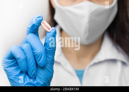 Pillola di vitamina in mano in guanti blu. La femmina sta tenendo un medicinale. Farmaci contro il coronavirus, 2019-nCoV, SARS-nCov, COVID-2019 outbreaking. Foto Stock