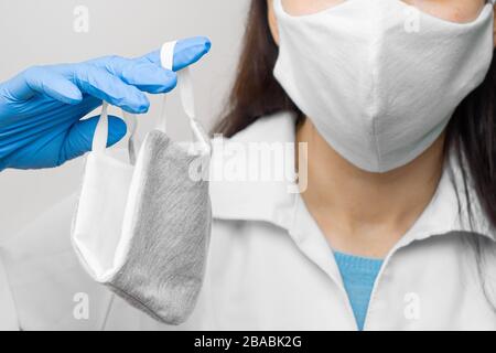 Proteggersi utilizzando una maschera medica. La donna è in possesso di una maschera respiratore protettiva da infezione da virus, pandemica durante la quarantena. Medico in un Foto Stock