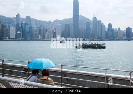 Hong Kong, Cina. 25 Marzo 2020. Una coppia con un ombrello siede al Victoria Harbour di Hong Kong. Più di 420,000 persone in tutto il mondo sono state infettate dal nuovo coronavirus, e il numero di morti per l’epidemia continua ad aumentare. Credit: Keith Tsuji/ZUMA Wire/Alamy Live News Foto Stock