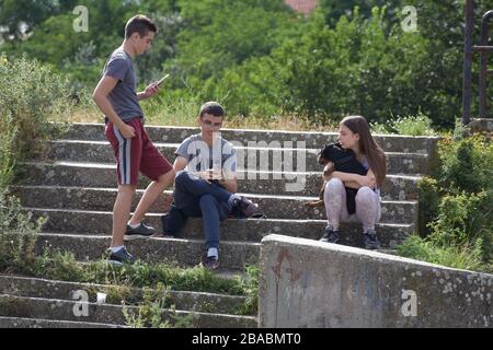 Passi di calcestruzzo vecchi overgrown con erba. Ci sono due ragazzi sui gradini, uno in piedi e l'altro seduto Foto Stock