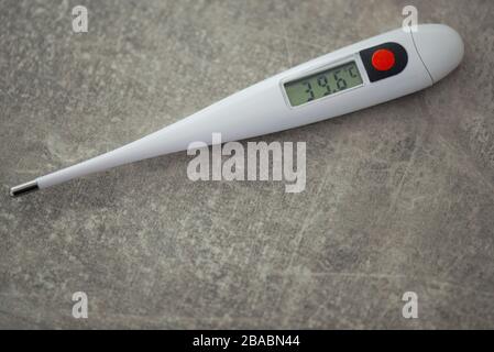 Termometro elettronico da primo piano per la misurazione della temperatura corporea su sfondo grigio Foto Stock