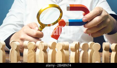 Businessman esamina il candidato migliore per il lavoro con una lente di ingrandimento. Reclutare nuovi lavoratori, cacciatori di teste, personale. Alla ricerca di lavoratori di talento. Checki Foto Stock