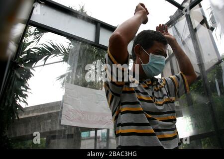 Giacarta, Indonesia. 25 Marzo 2020. I residenti che saranno attivi in luoghi pubblici, utilizzano la camera di disinfezione di Blok M, Giacarta Sud, Indonesia. In questa camera di sterilizzazione tutto il corpo della persona verrà spruzzato con liquido disinfettante. Questo liquido disinfettante ha la funzione di uccidere il virus della corona che si attacca ai vestiti o al corpo della persona, per anticipare la diffusione del virus della corona (COVID-19) negli spazi pubblici. (Foto di Kuncoro Widyo Rumpoko/Pacific Press) Credit: Pacific Press Agency/Alamy Live News Foto Stock