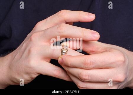 Un uomo toglie un anello di nozze da un dito della sua mano. Primo piano. Foto Stock