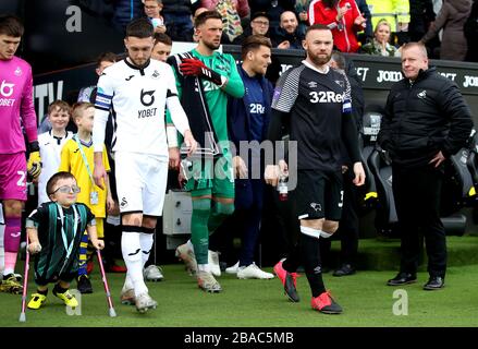 Il capitano della Derby County Wayne Rooney (a destra) e il capitano della città di Swansea Matt Grimes guidano le loro squadre fuori dal tunnel e sul campo prima dell'inizio della partita Foto Stock