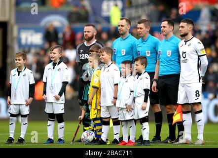 Derby County Captain Wayne Rooney (a sinistra) e Swansea City Captain Matt Grimes posa per una foto con i quattro ufficiali e le mascotte prima dell'inizio della partita Foto Stock