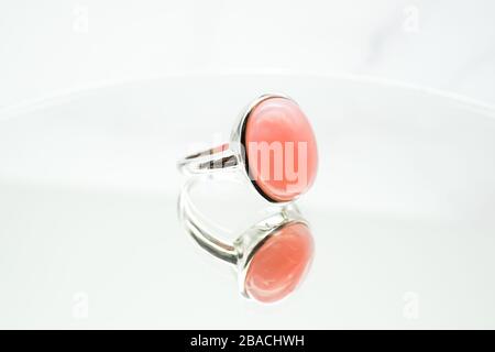 Primo piano di un anello ovale rosa su un superficie bianca Foto Stock