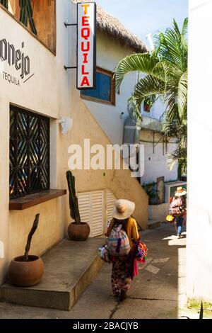 I venditori ambulanti di strada camminano lungo un vicolo stretto in Sayulita, Nayarit, Messico. Foto Stock